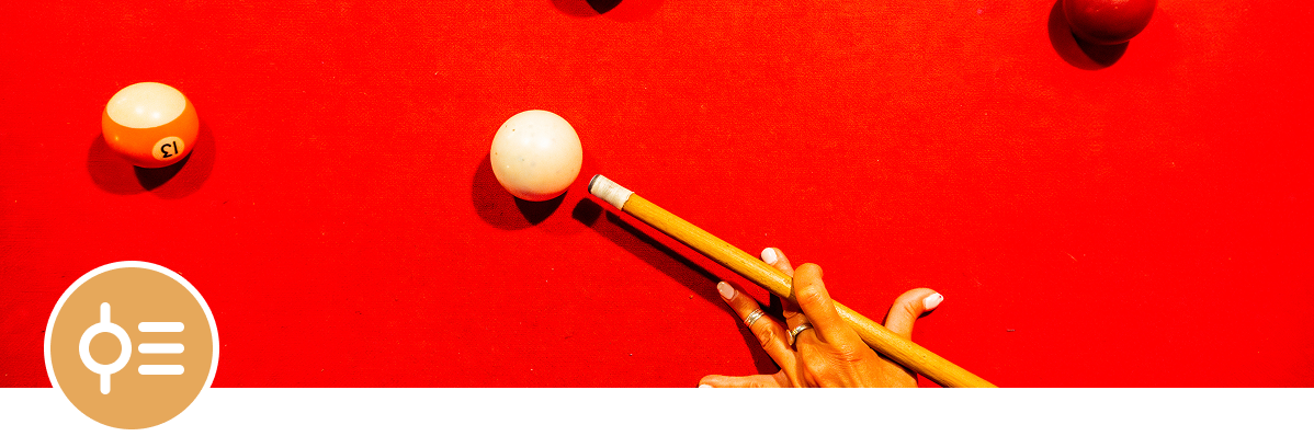 Person playing pool, vibrant red surface
