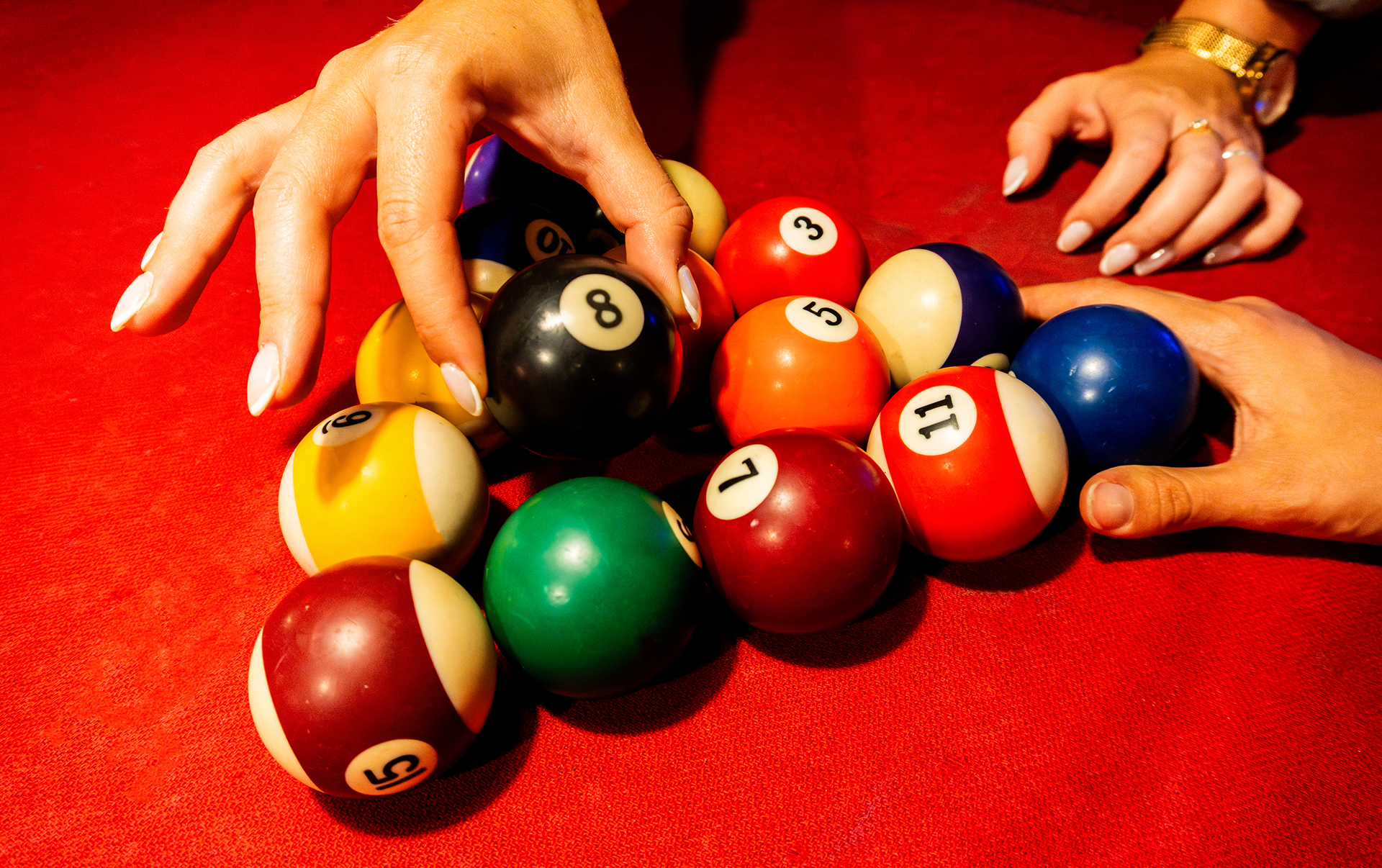 Hands arranging colorful billiard balls